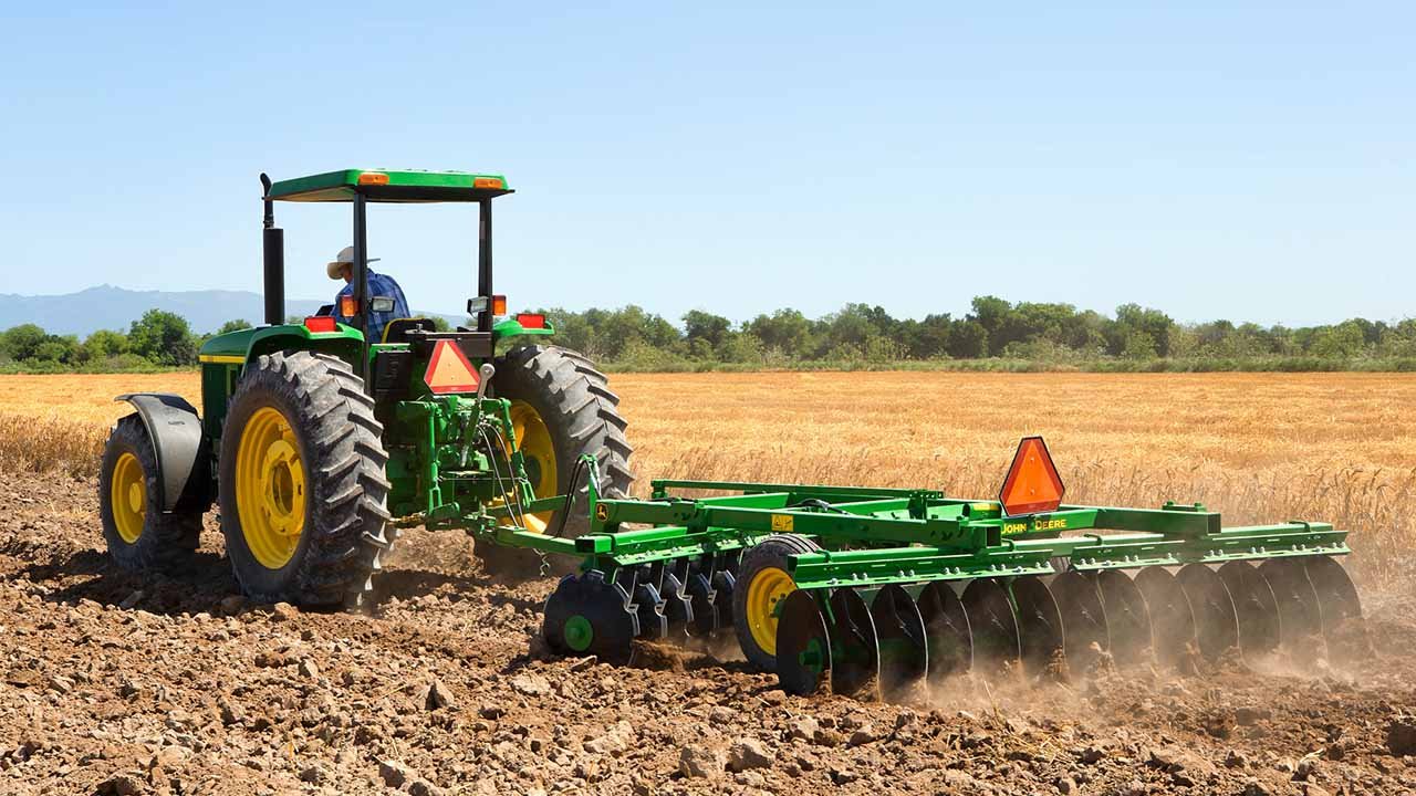 Hombre conduciendo un tractor mientras ara la tierra en un campo agrícola.
